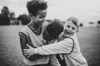 three young athletes give each other a hug